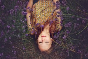 Woman laying on the earth wrapped in scarf surrounded by flowers woman's clothing protection wise fashion| The Sublime Woman