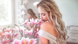 Woman holding beautiful pink flower feminine energy femininity | The Sublime Woman