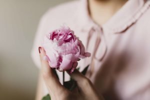 Woman holding beautiful pink flower feminine energy femininity | The Sublime Woman