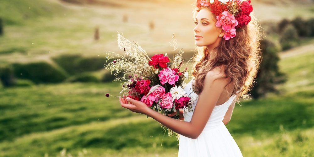 Woman in the field with flowers in her hand and in her hair energy exchange rules | The Sublime Woman