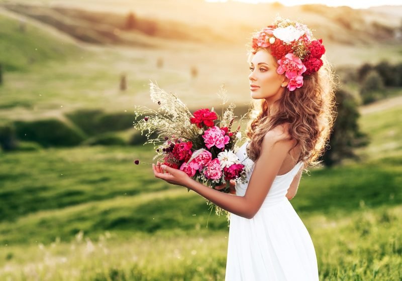Woman in the field with flowers in her hand and in her hair energy exchange rules | The Sublime Woman