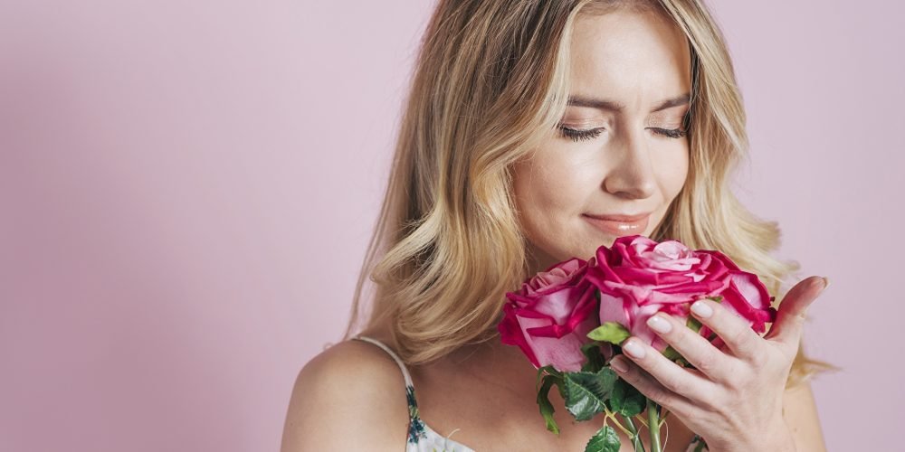 Practice Exercise to Increase Feminine Energy, Beautiful woman holding flowers smelling roses, Practice connecting with the womb | The Sublime Woman