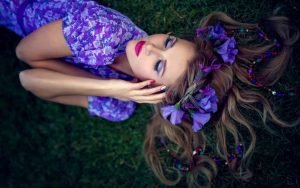 Practice Woman's Sahasrara Chakra Healing beautiful woman in violet laying on the earth with purple flowers | The Sublime Woman