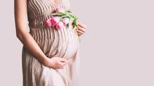 Pregnant woman holding her belly with flowers — symbol of pregnancy and spiritual meaning of miscarriage.
