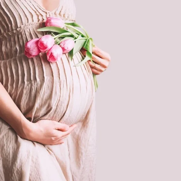 Pregnant woman holding her belly with flowers — symbol of pregnancy and spiritual meaning of miscarriage.