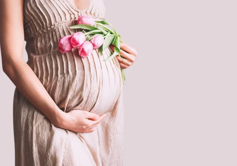 Pregnant woman holding her belly with flowers — symbol of pregnancy and spiritual meaning of miscarriage.